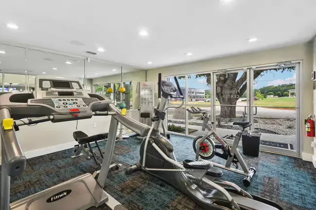 Gym with treadmills, elliptical, and stationary bikes. Mirrored wall and windows to outside.