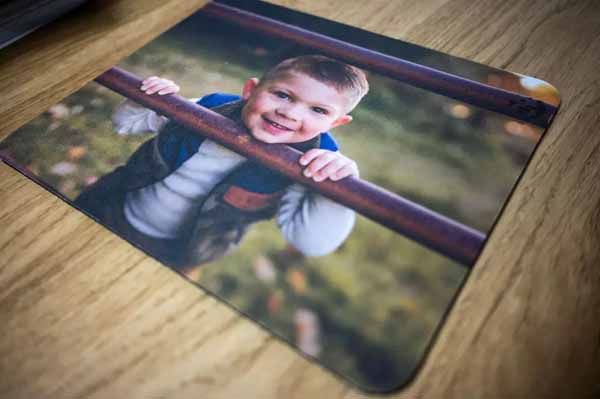 A mouse pad with a picture of a young boy on it.