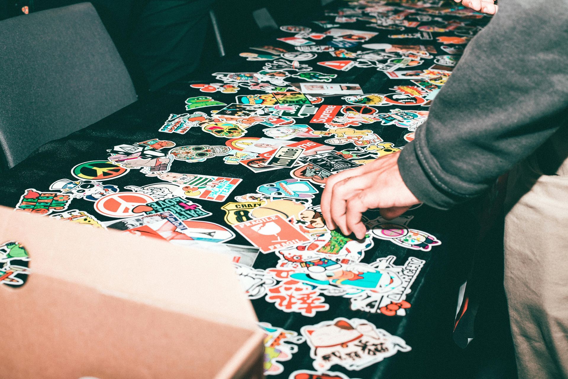 A person is putting a sticker on a table full of stickers