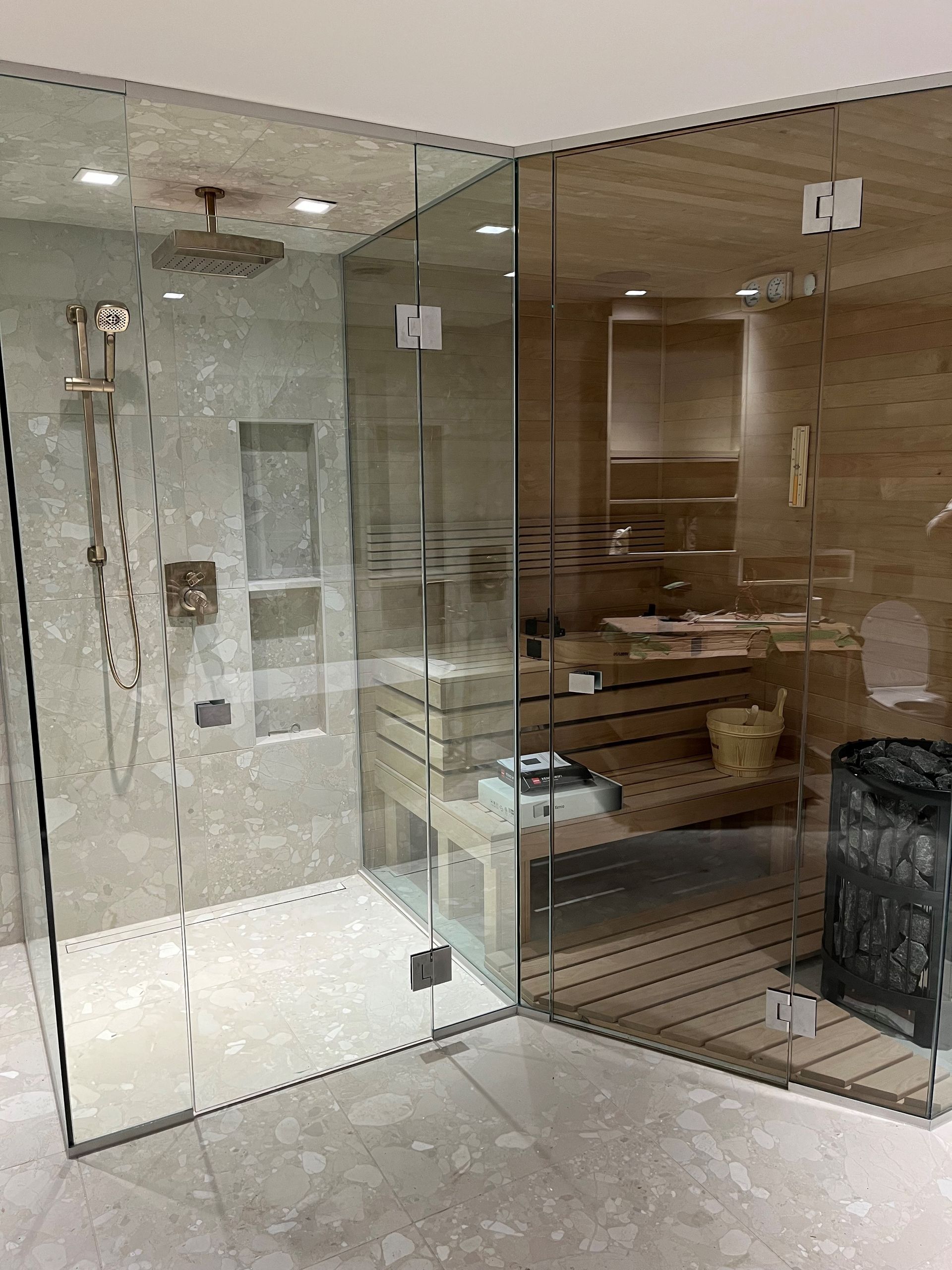 Douche vitrée et sauna avec bancs en bois et murs en pierre.