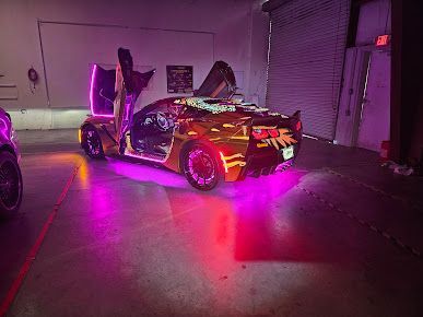 A car is parked in a garage with purple lights on it.