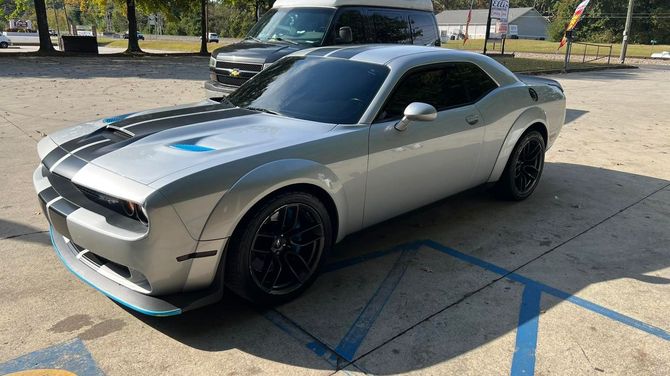 A silver dodge challenger is parked in a handicapped parking spot.