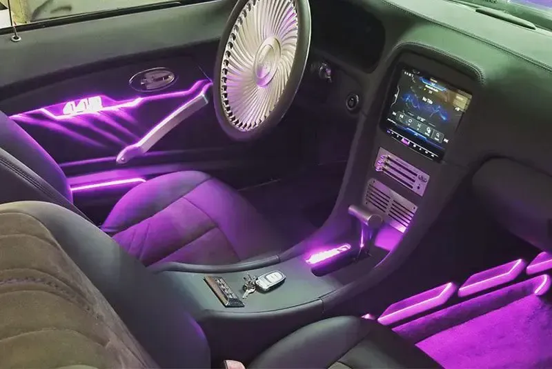 The interior of a car with purple lights and a steering wheel.
