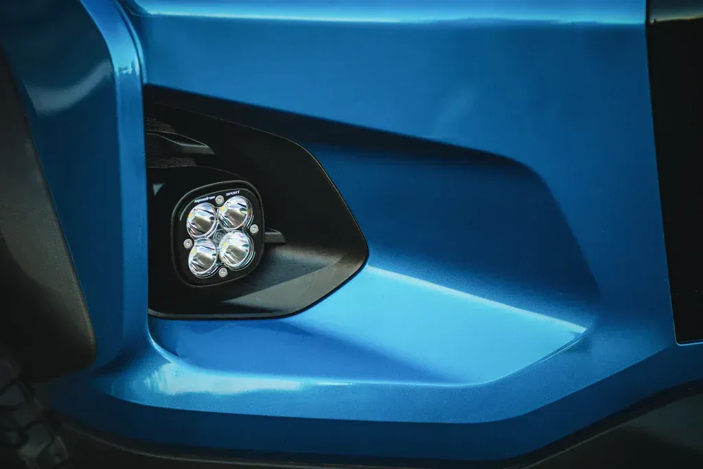 A close up of a blue car bumper with a light on it.