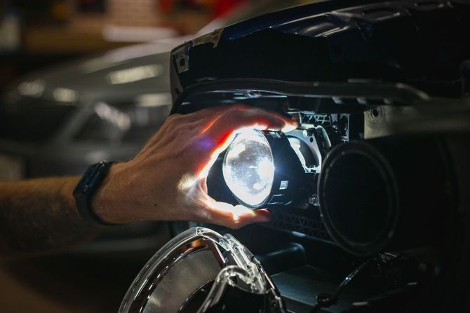 A person is fixing a car headlight in a garage.