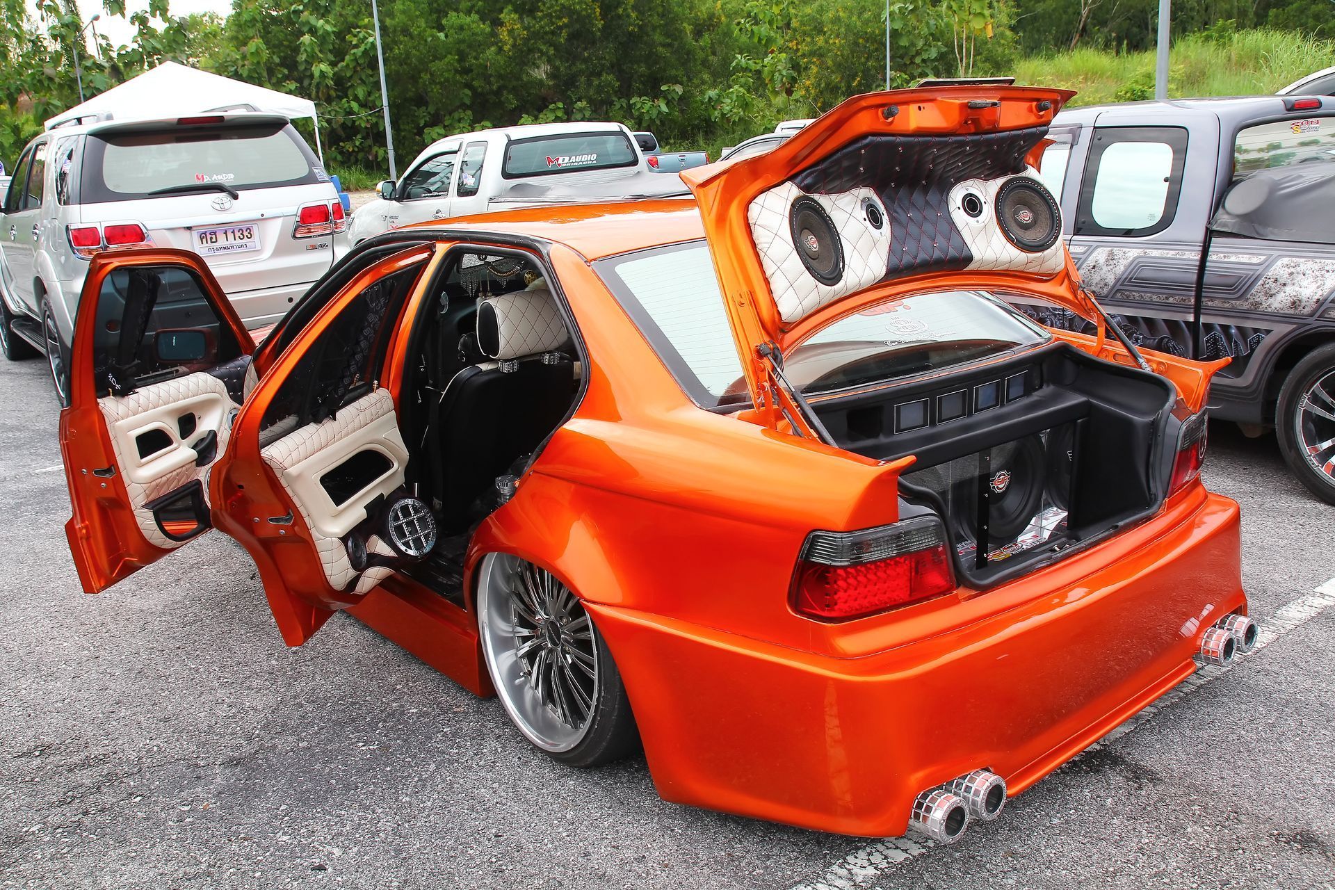 An orange car with the trunk open is parked in a parking lot.