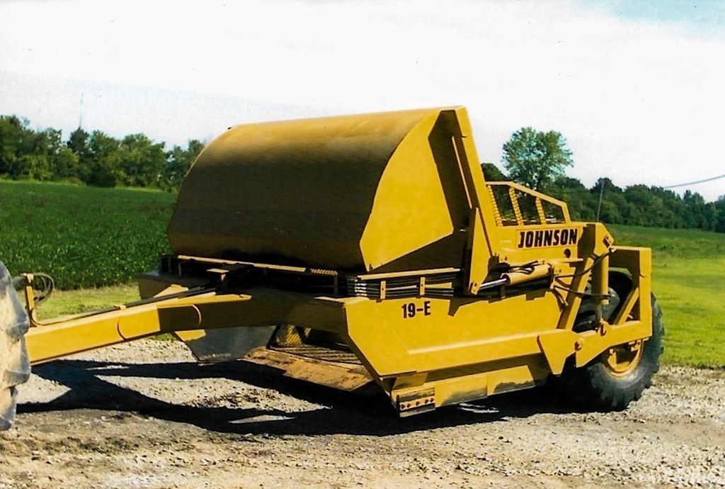 A yellow tractor is parked on a dirt road