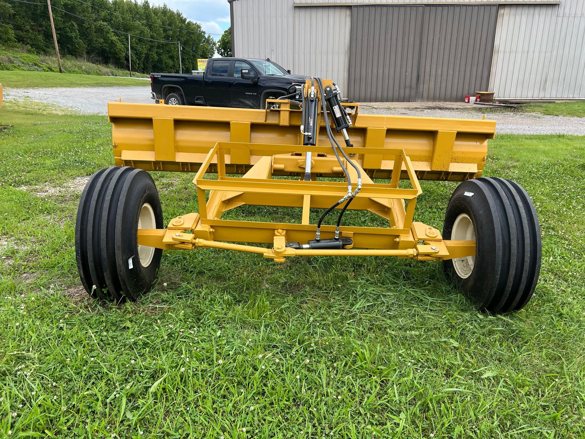 A yellow tractor is parked in the grass next to a truck.