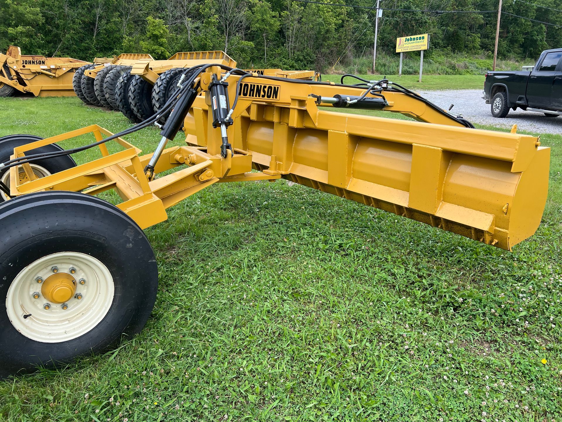 A yellow tractor is parked in the grass next to a truck.