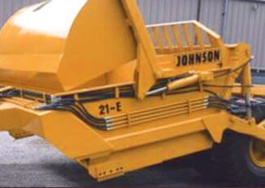 A yellow johnson dumpster is parked in front of a building