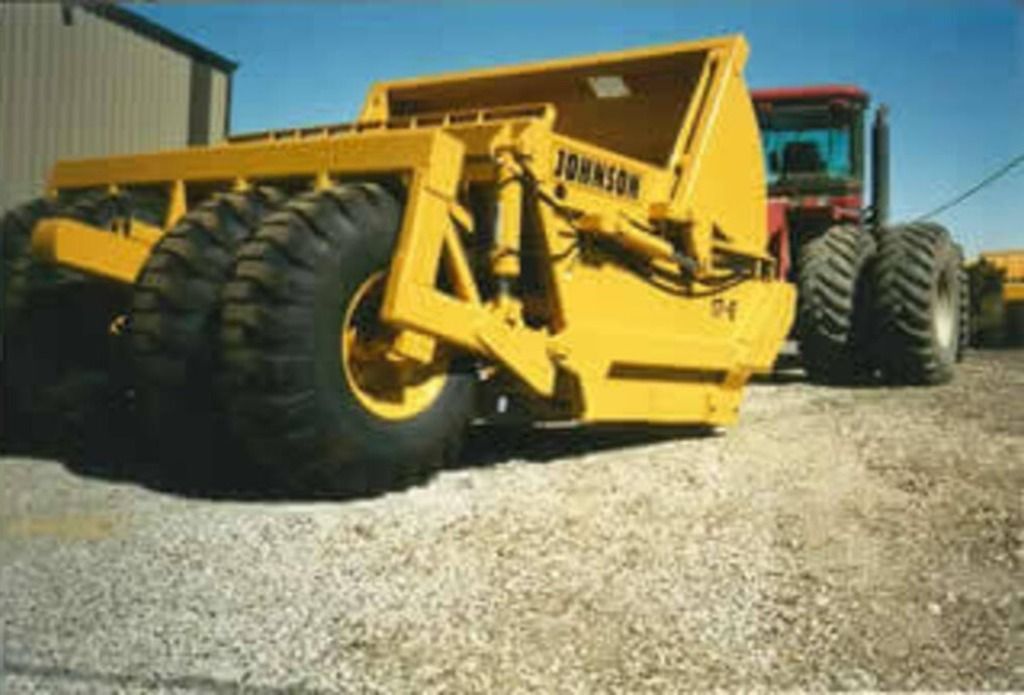 A yellow johnson tractor is parked in a gravel lot