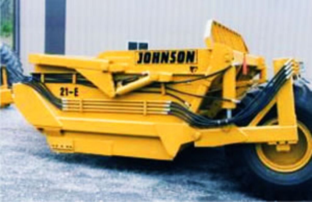 A yellow johnson tractor is parked in front of a building