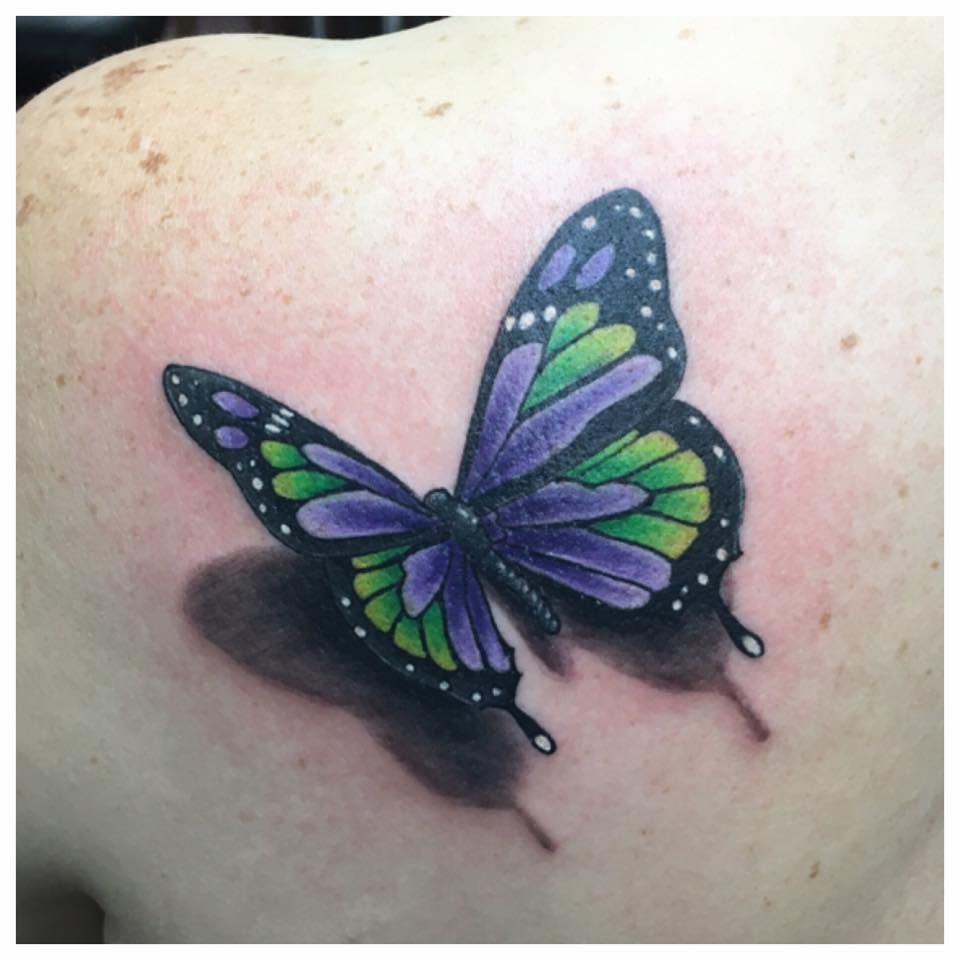 A woman has a purple and green butterfly tattoo on her back.