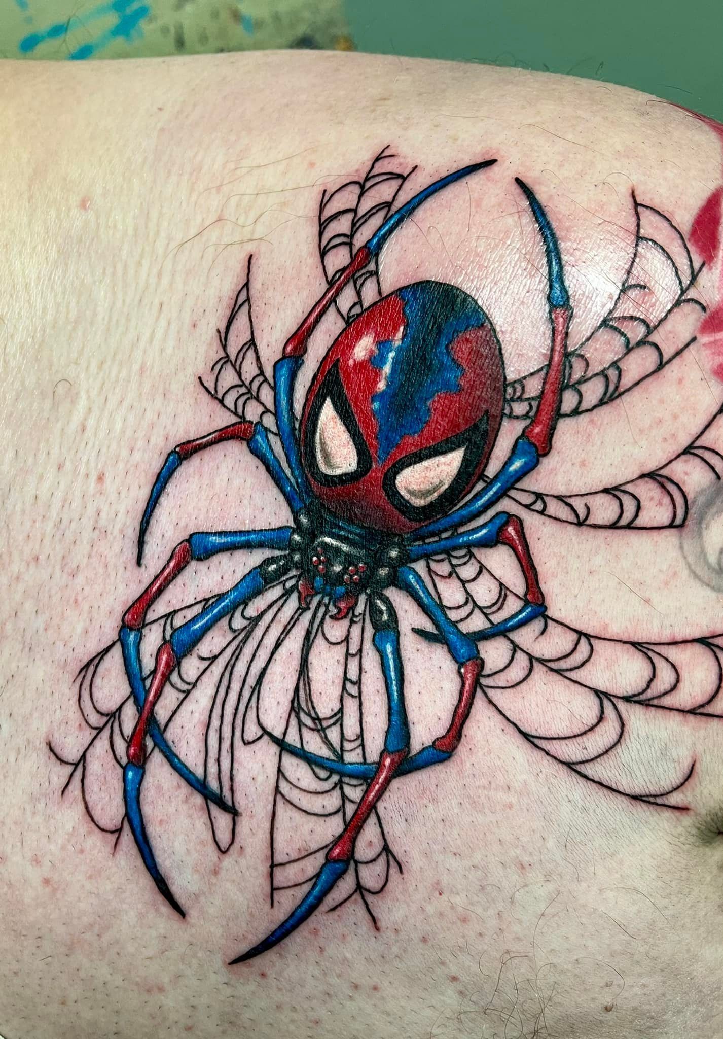 A close up of a tattoo of a spider on a person 's leg