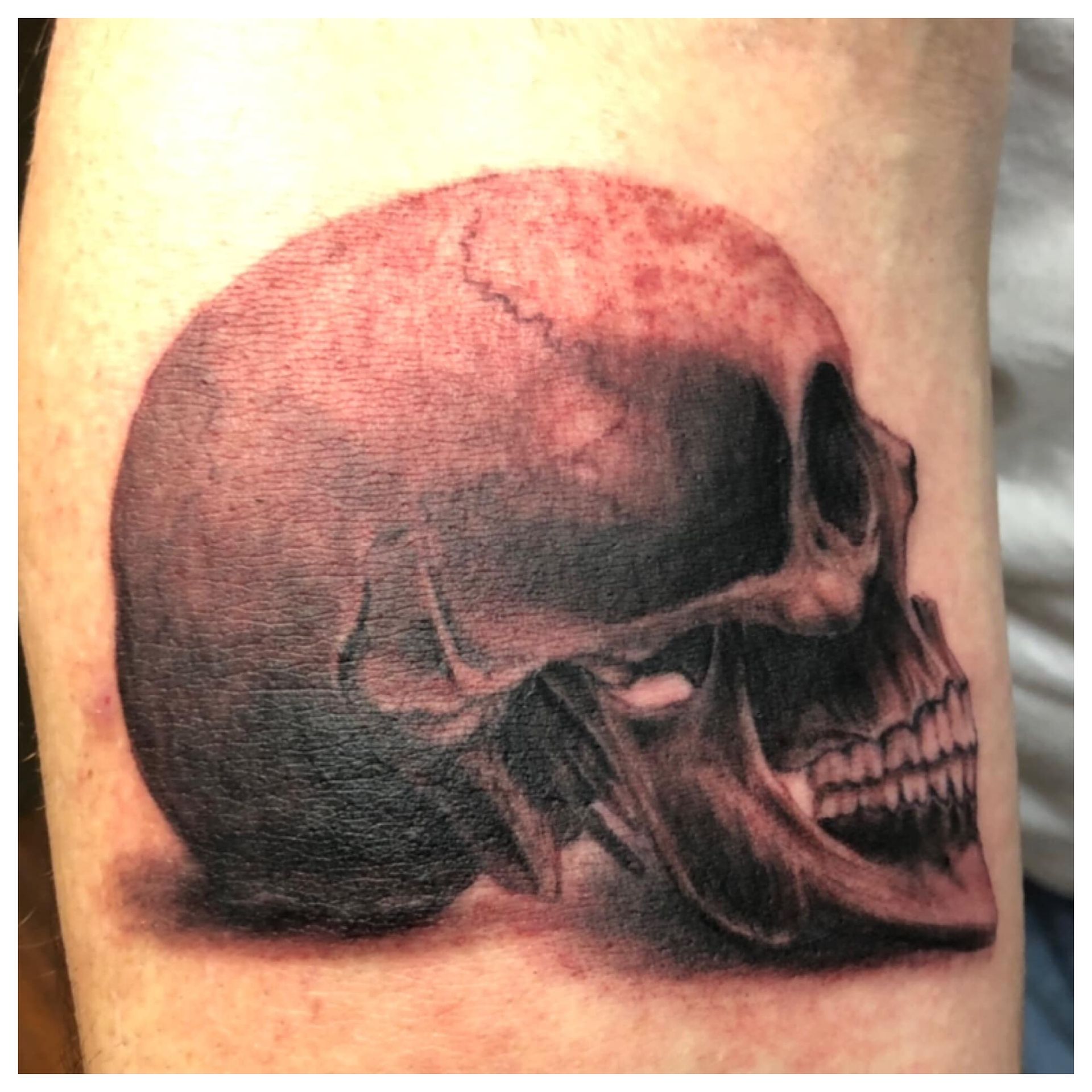 A close up of a tattoo of a skull on a person 's arm.