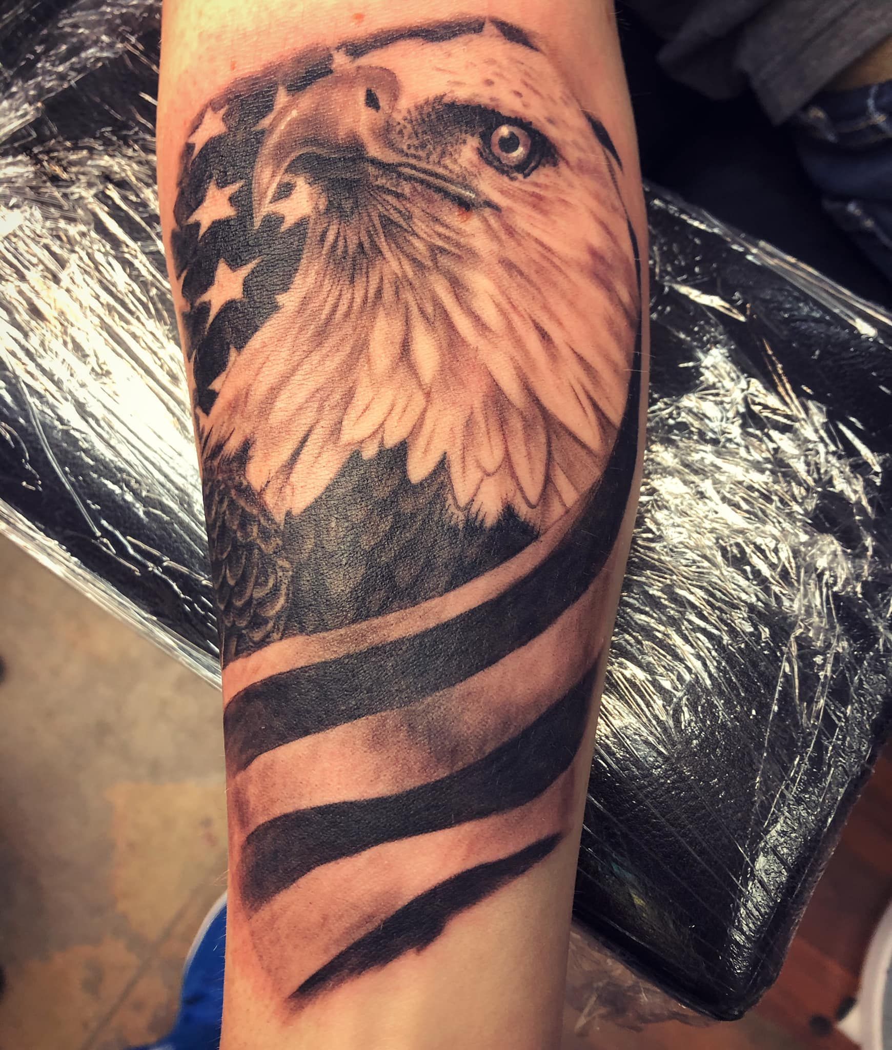 A tattoo of an eagle and an american flag on a person 's arm
