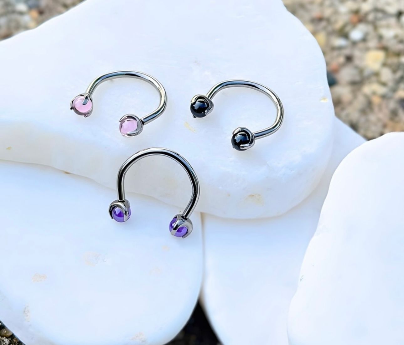 Three horseshoe earrings are sitting on top of a white rock.