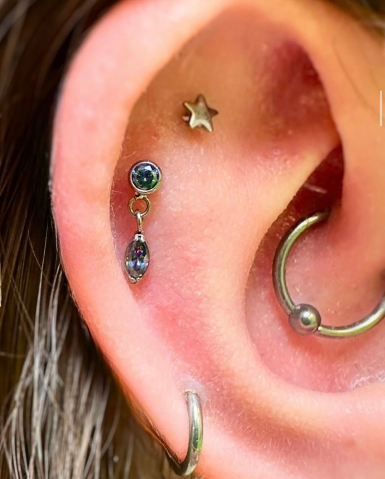 A close up of a woman 's ear with multiple piercings.