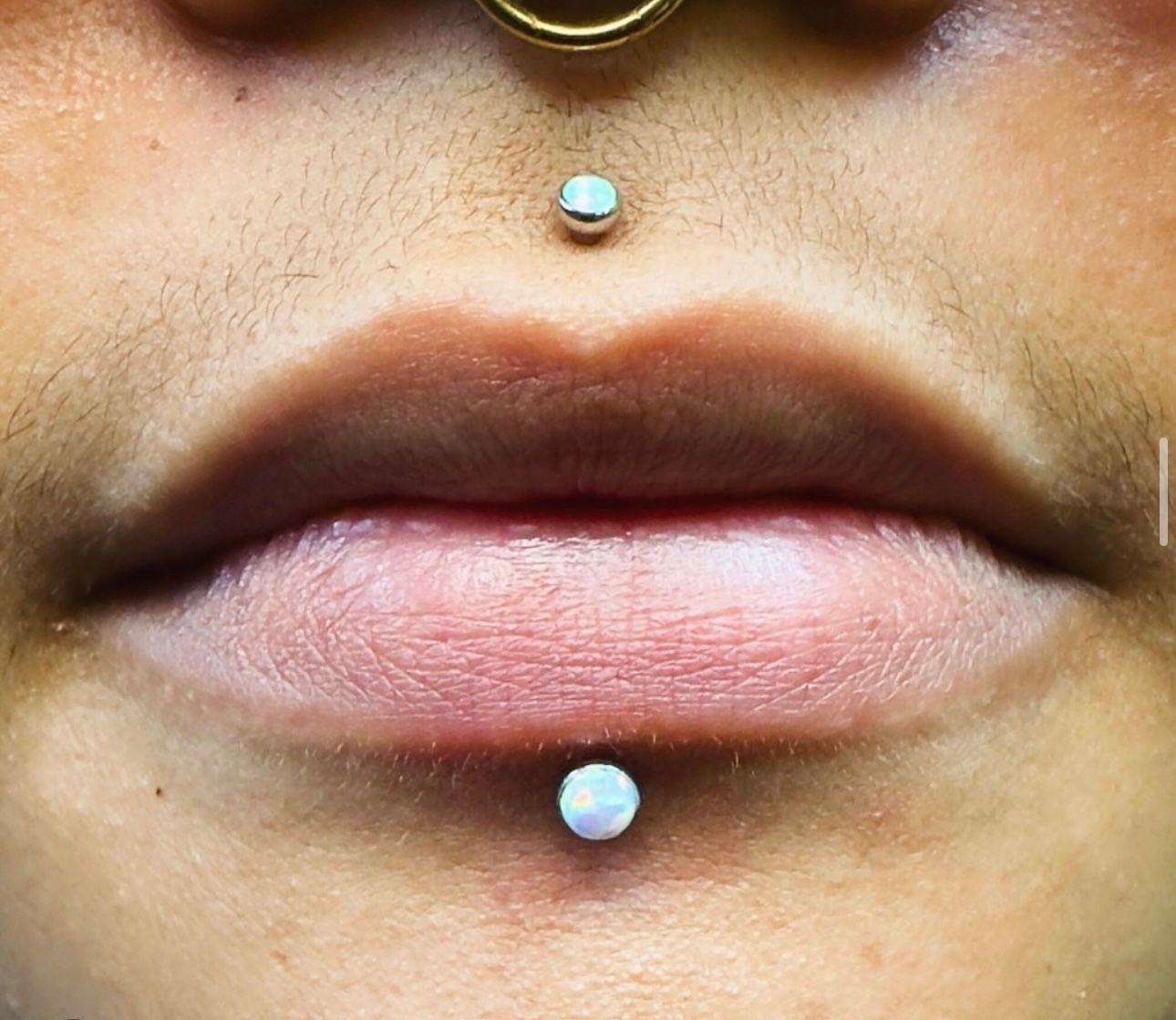 A close up of a person 's lips with two piercings.