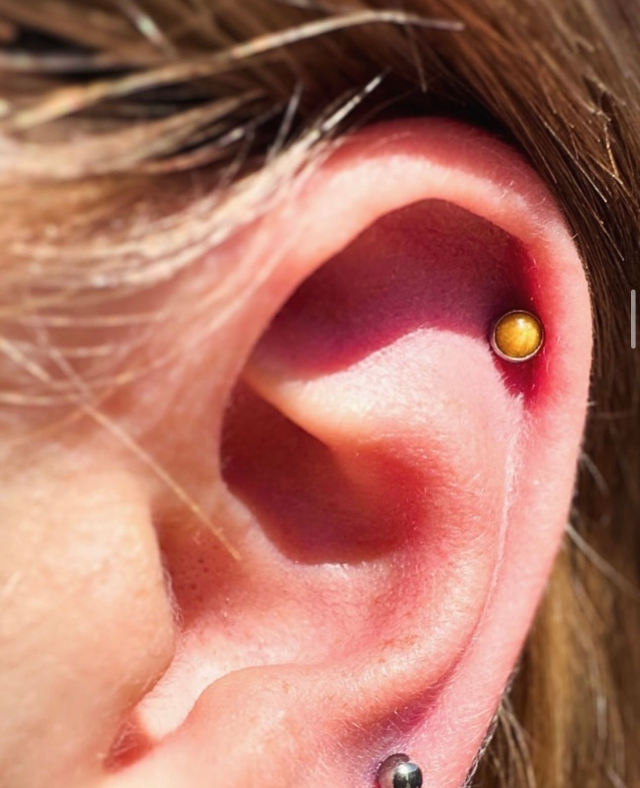 A close up of a woman 's ear with a piercing in it