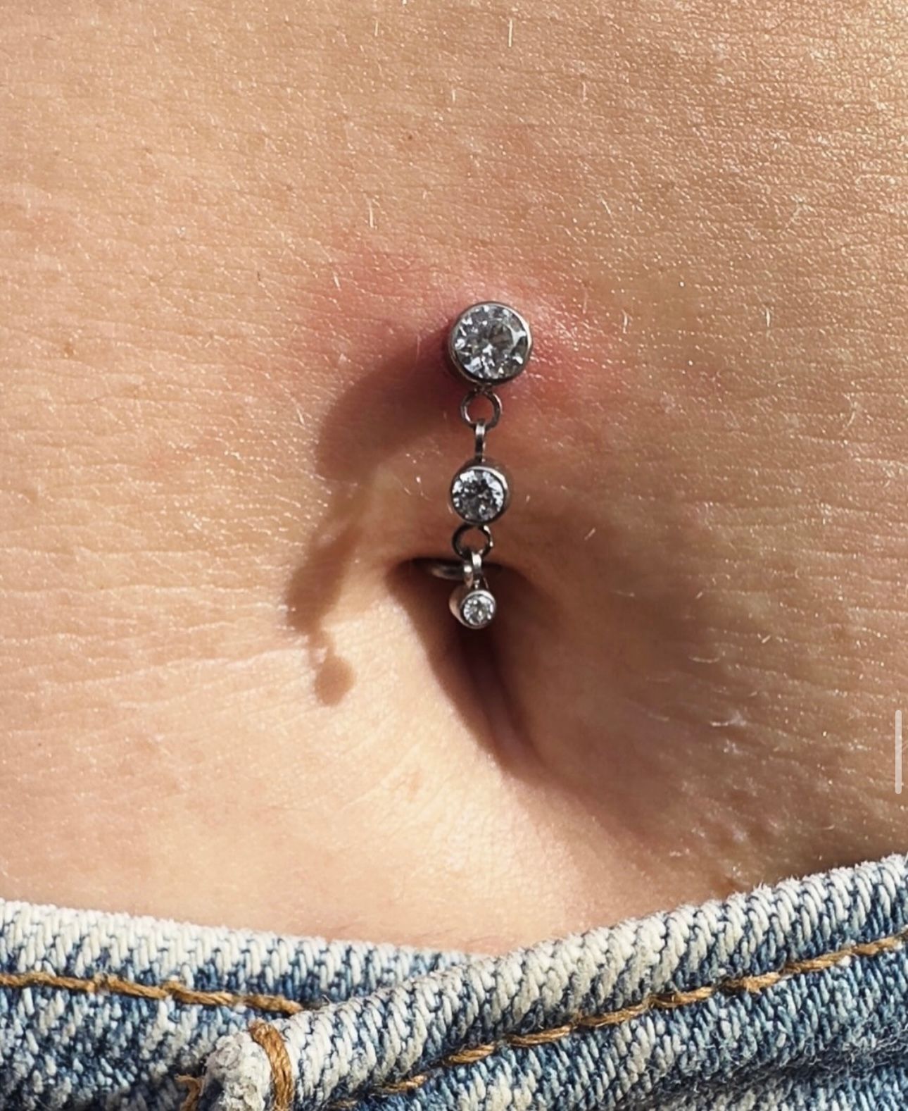 A close up of a person 's belly with a piercing