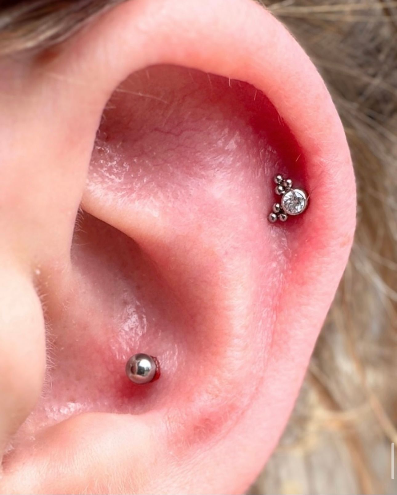 A close up of a person 's ear with two piercings.
