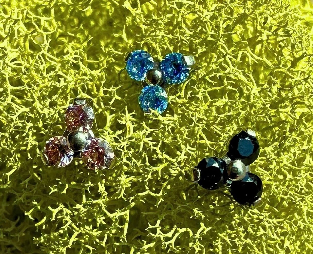 Three earrings are sitting on a yellow surface