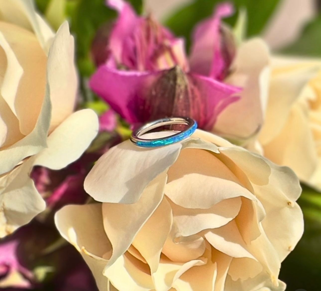 A blue ring is sitting on top of a white rose