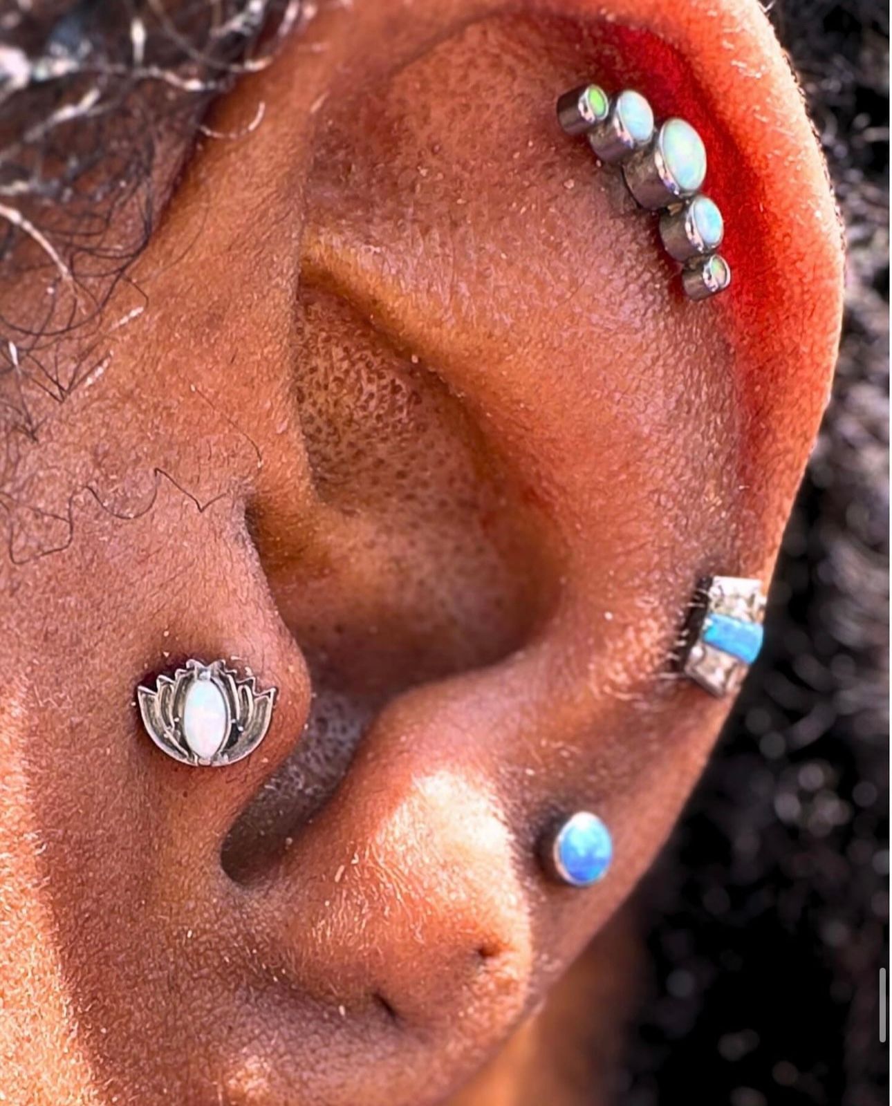 A close up of a woman 's ear with multiple piercings.