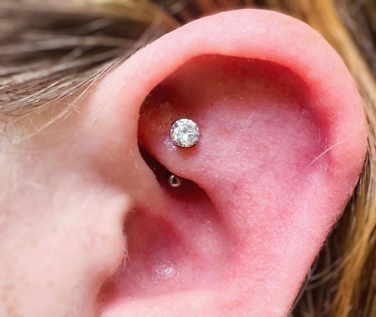 A close up of a woman 's ear with a piercing.