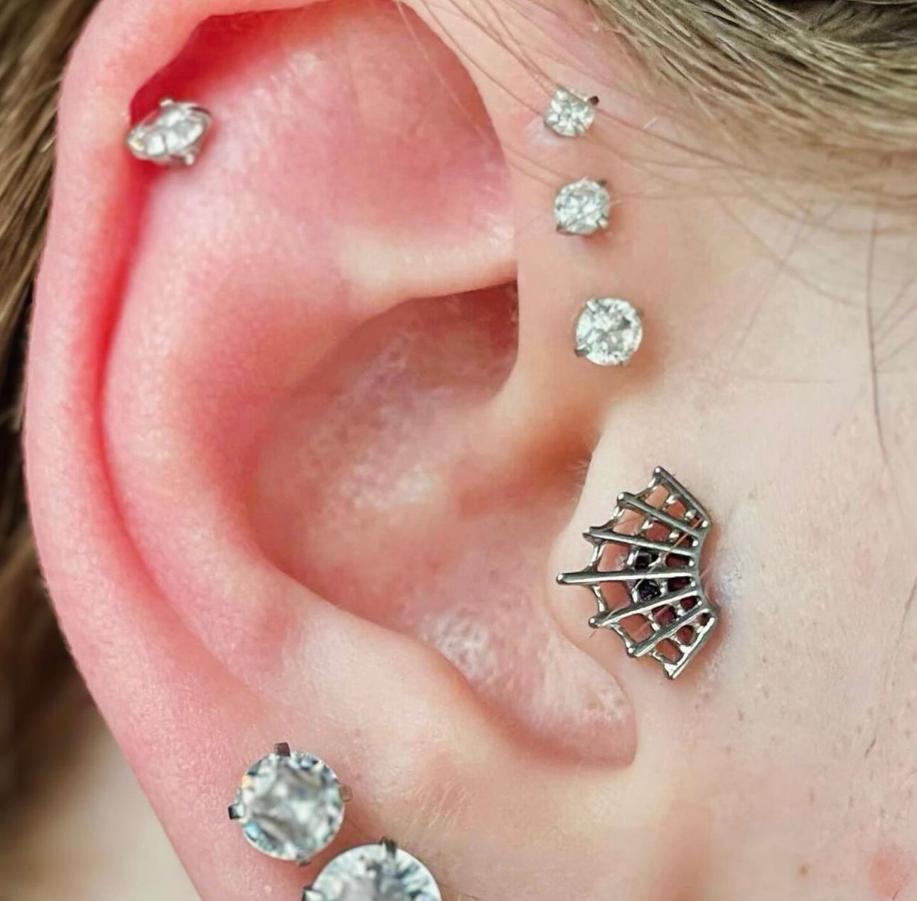 A close up of a woman 's ear with multiple piercings