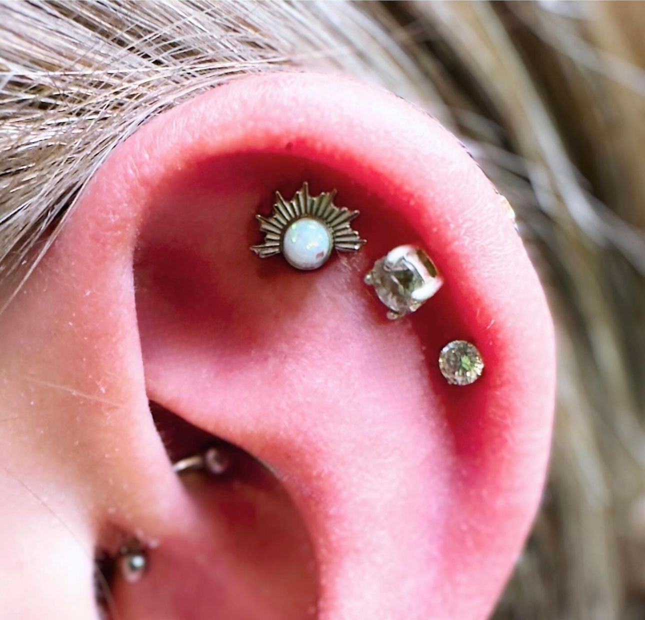 A close up of a woman 's ear with multiple piercings