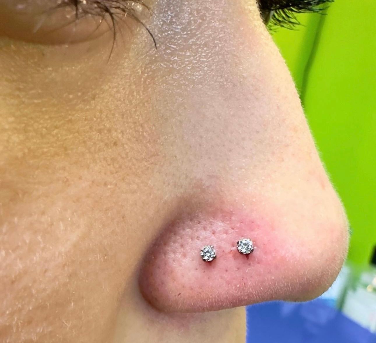 A close up of a woman 's nose with two earrings in it.