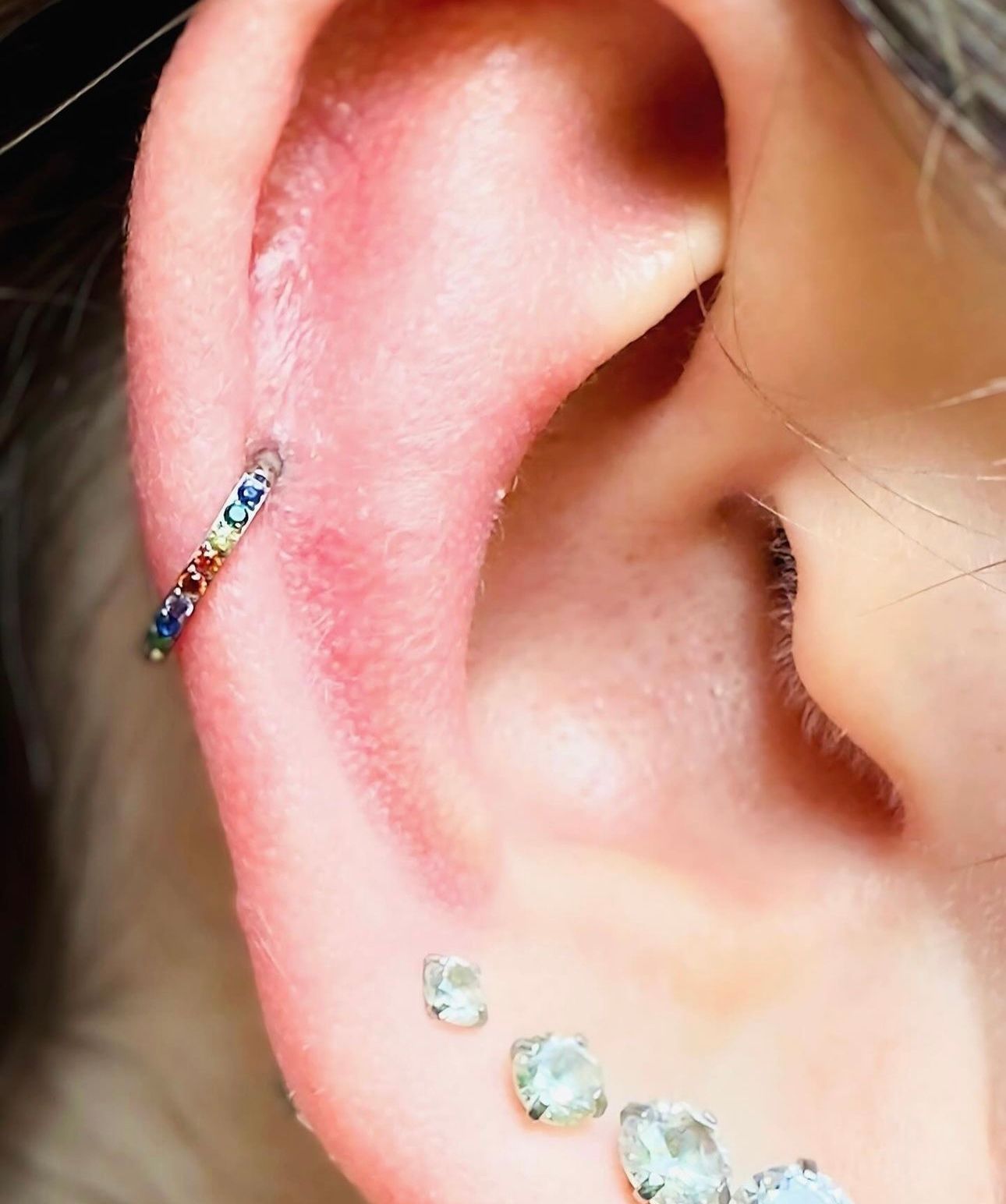 A close up of a woman 's ear with multiple piercings