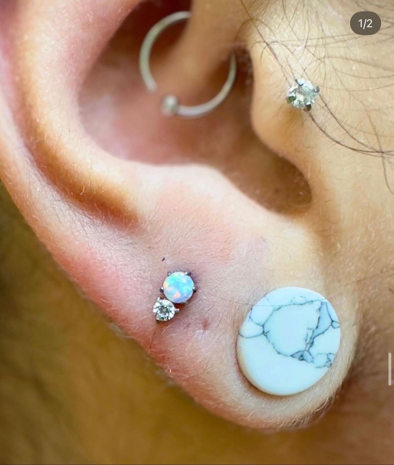 A close up of a person 's ear with earrings and a piercing.
