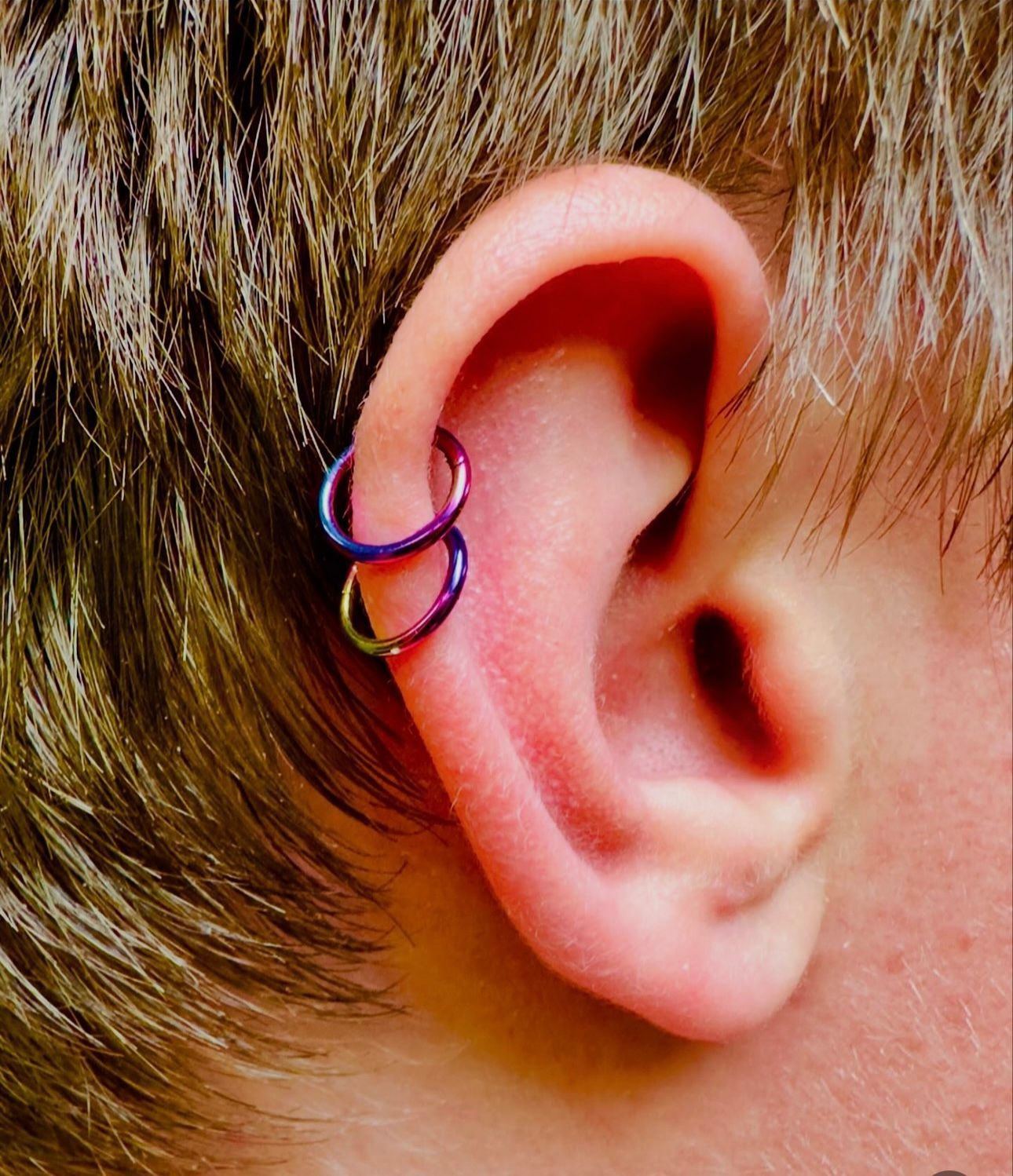 A close up of a person 's ear with two rings on it