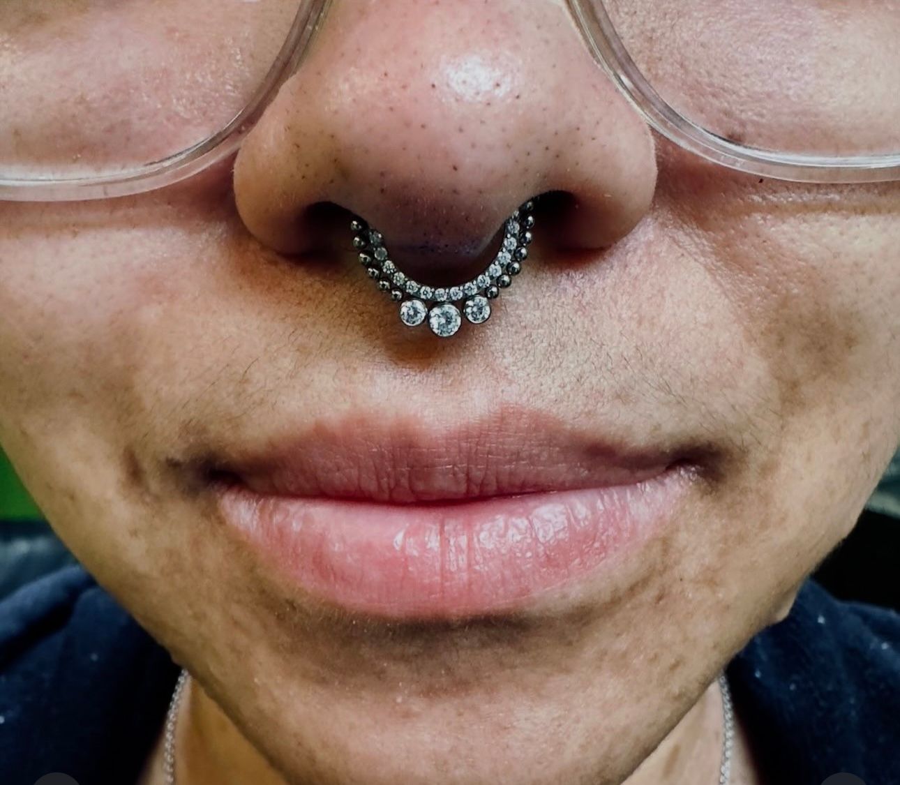 A close up of a woman 's face with glasses and a nose ring