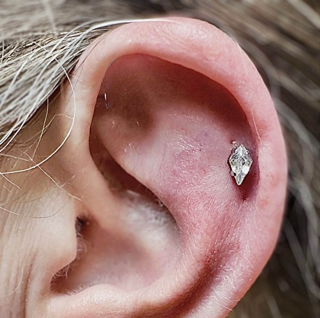 A close up of a woman 's ear with a diamond in it