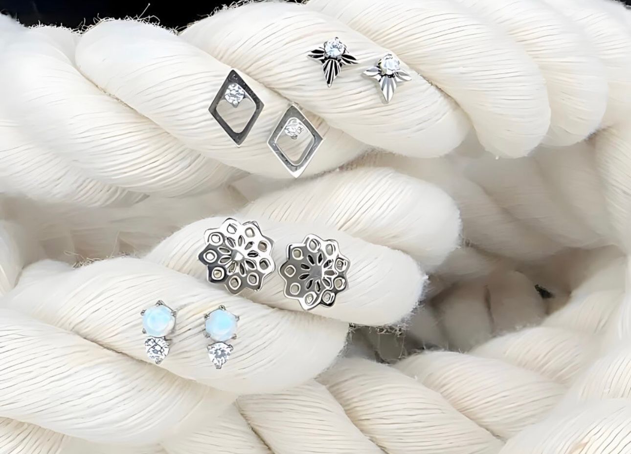 A pair of earrings sitting on top of a white rope.