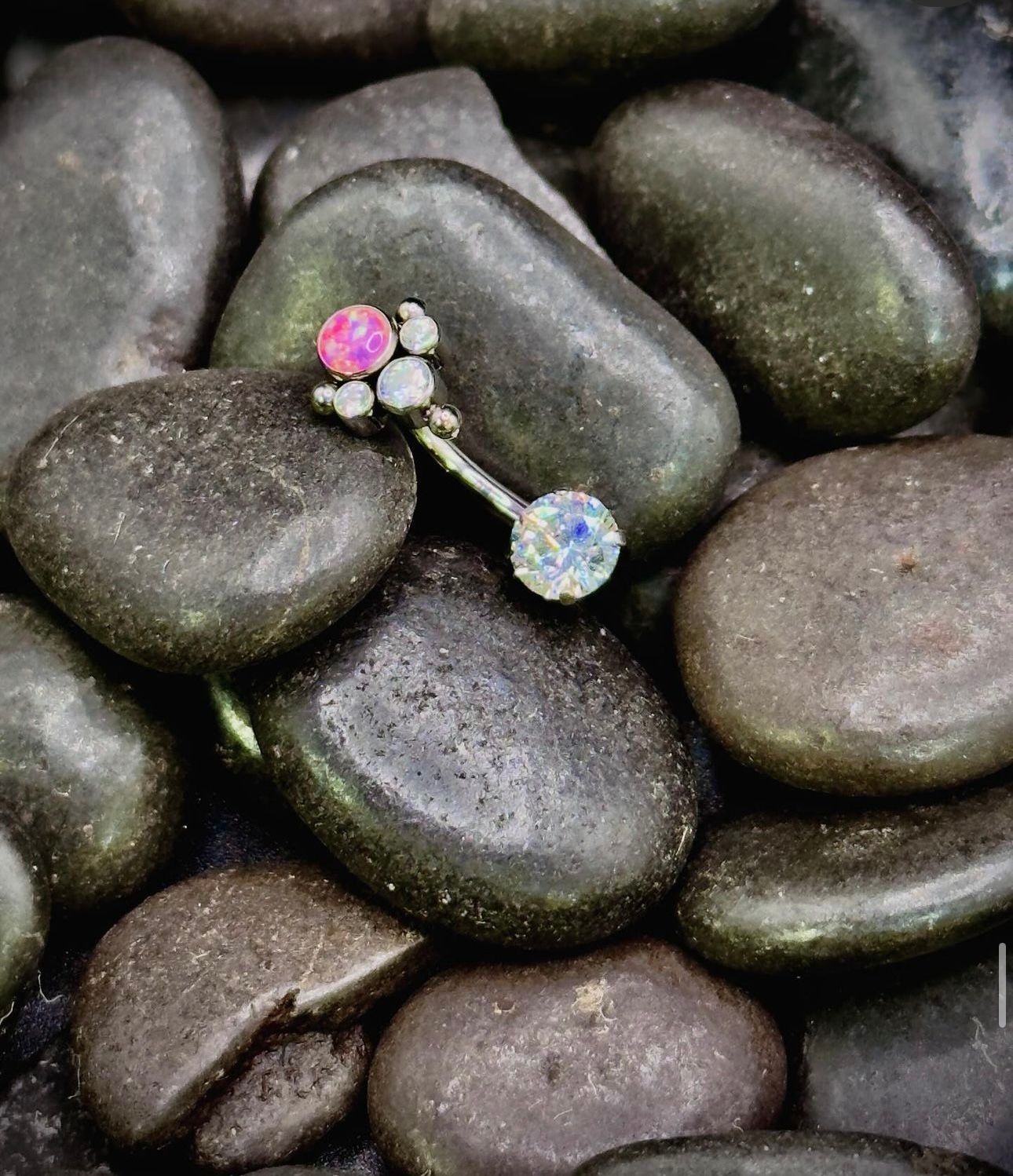 A belly button ring is sitting on top of a pile of rocks.