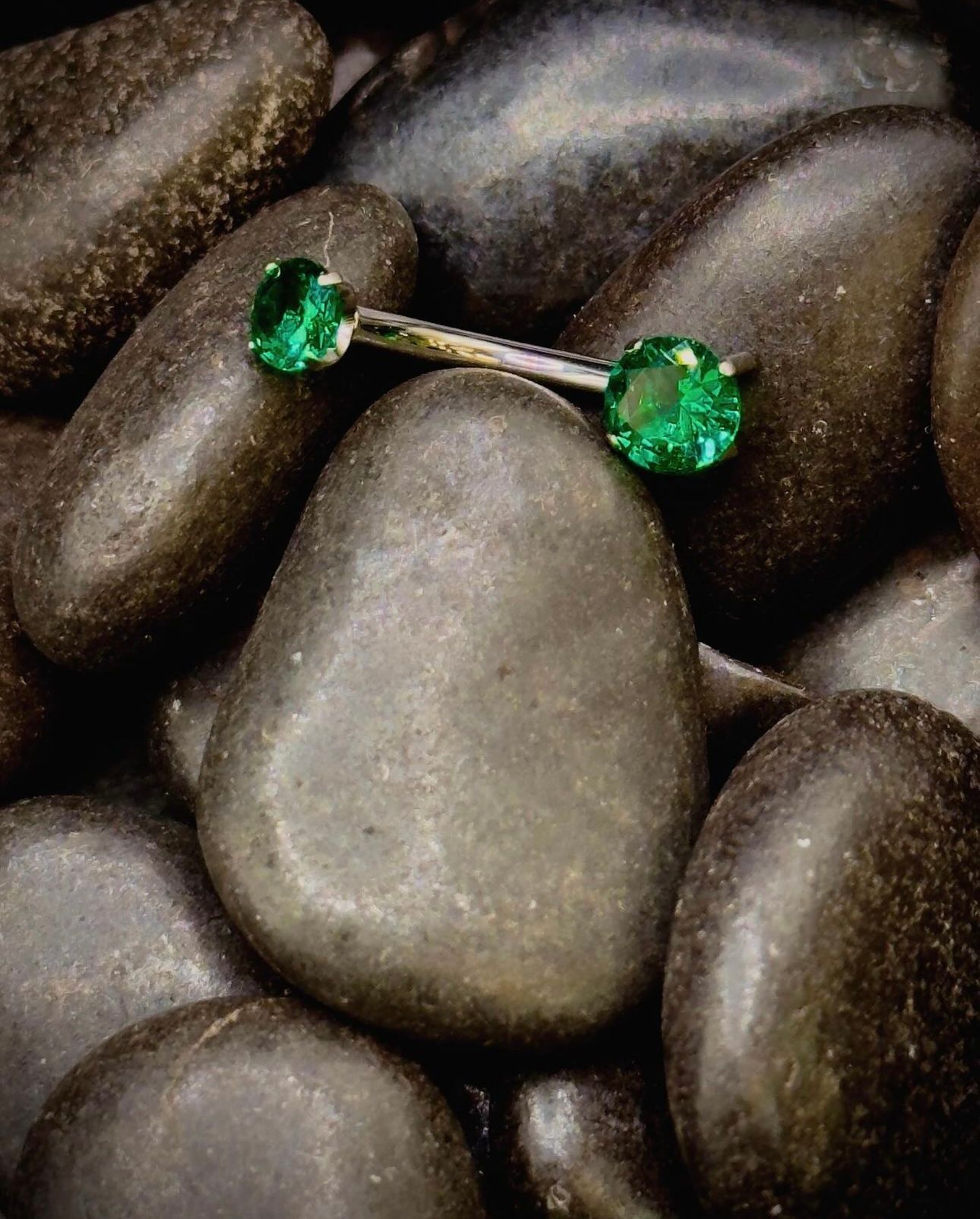 A pair of emerald earrings are sitting on top of a pile of rocks.