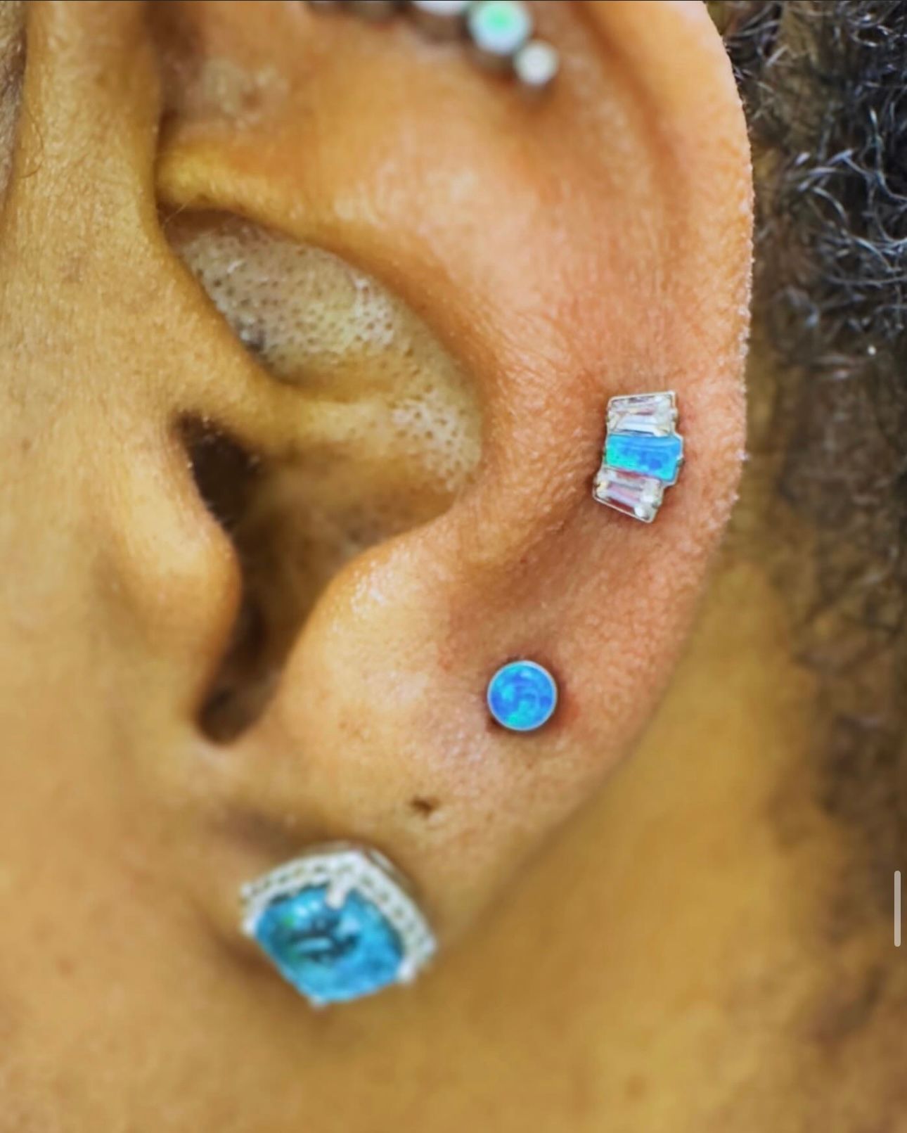 A close up of a woman 's ear with three piercings.