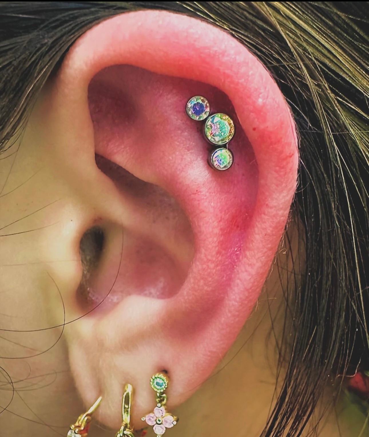 A close up of a woman 's ear with multiple piercings