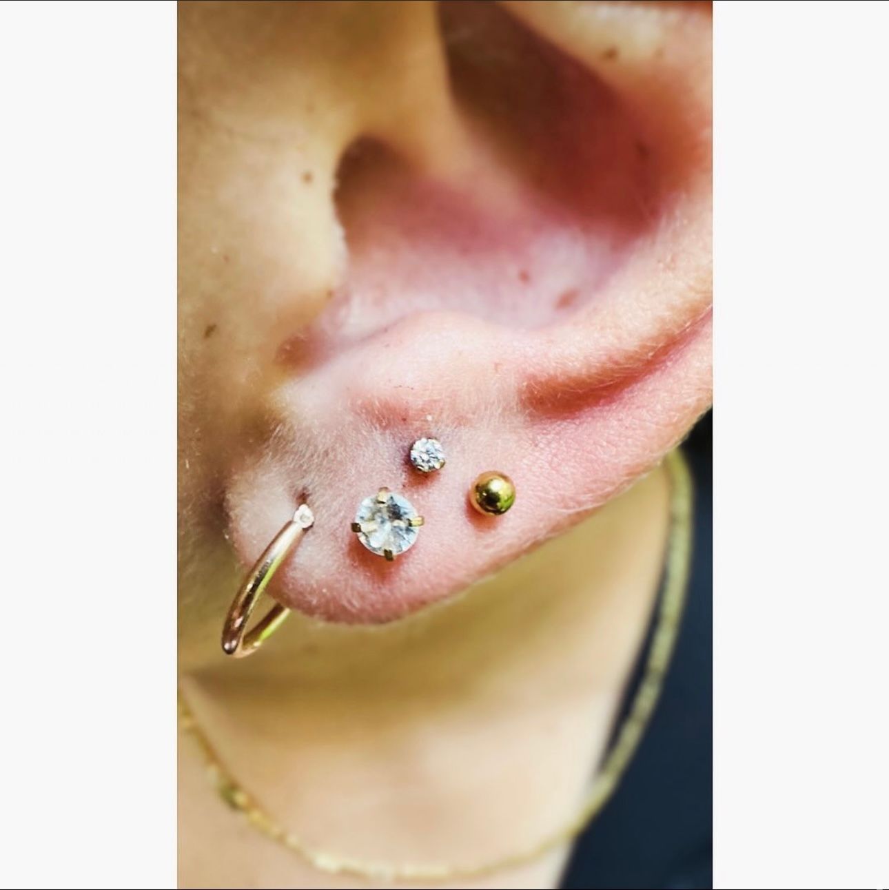 A close up of a person 's ear with multiple piercings.