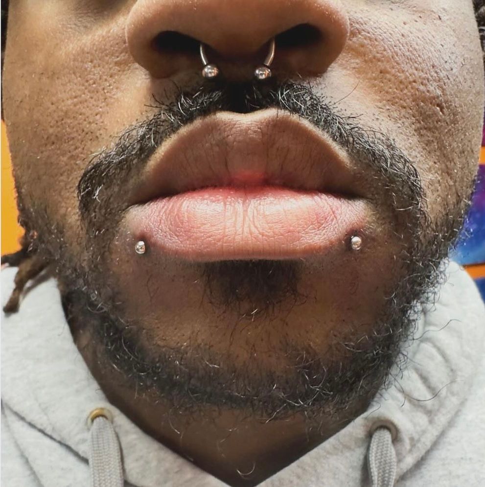 A close up of a man 's face with a beard and piercings