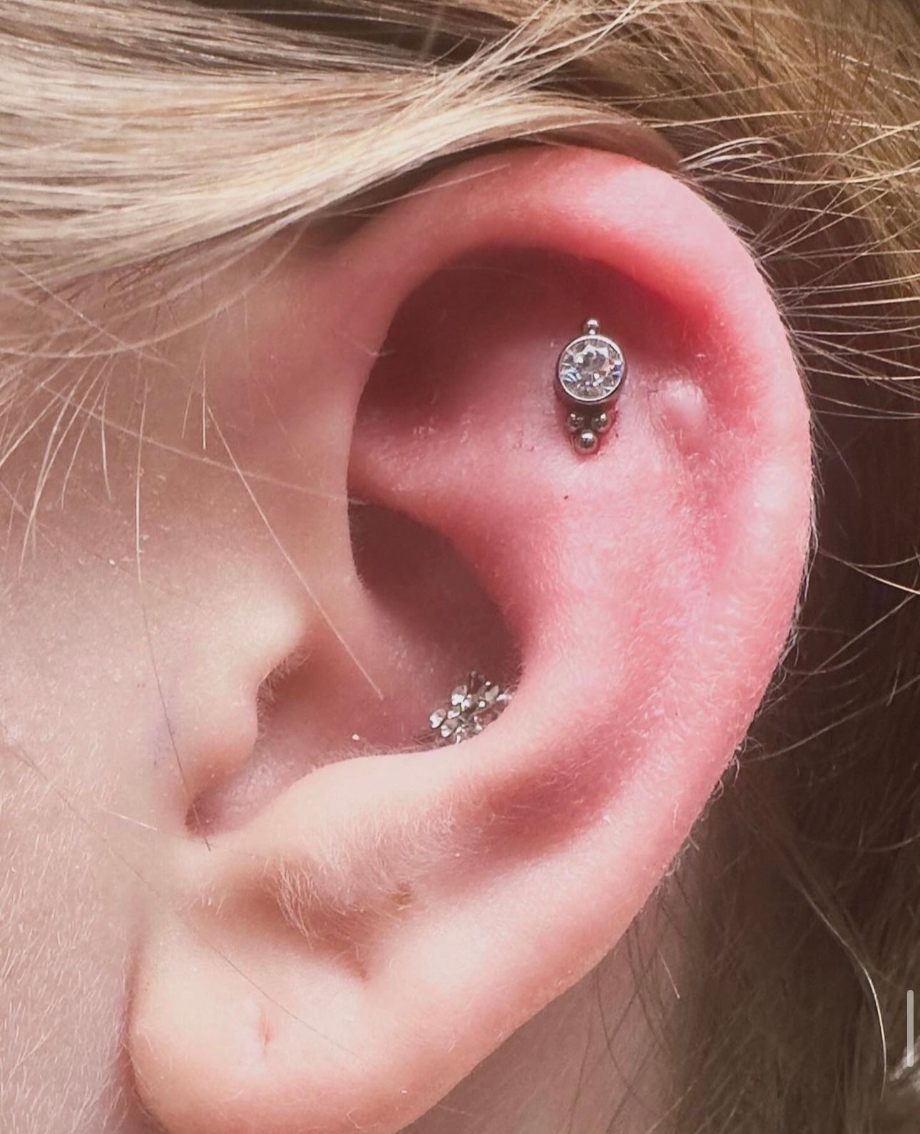A close up of a woman 's ear with a piercing in it