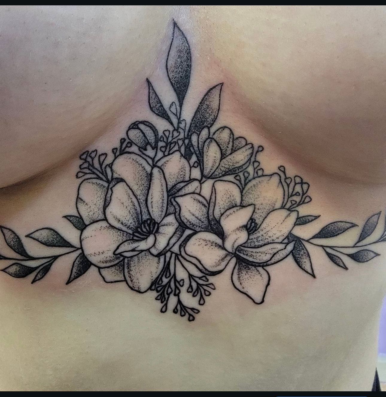 A tattoo of flowers and leaves on a woman 's chest