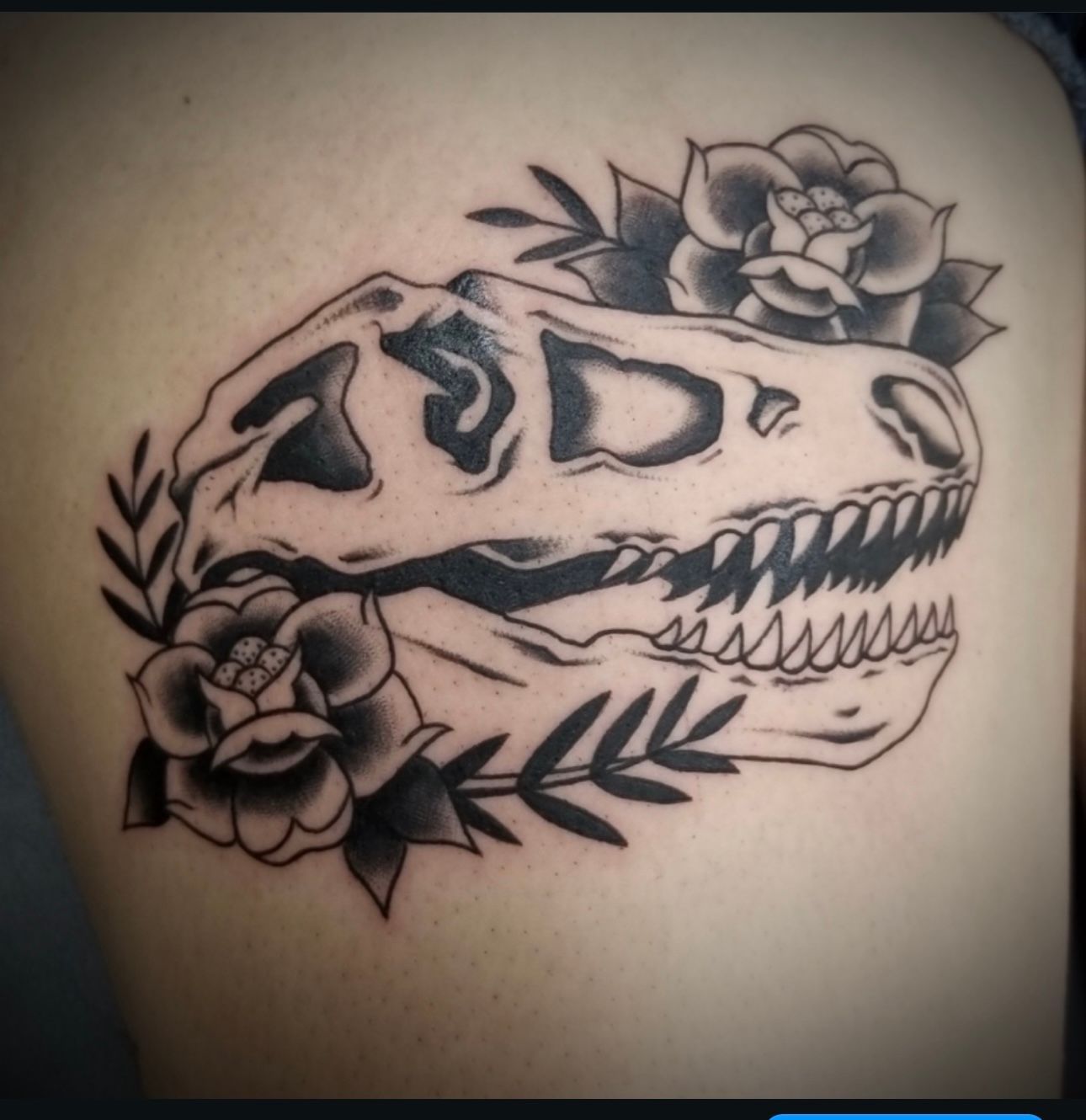 A black and white tattoo of a dinosaur skull with roses