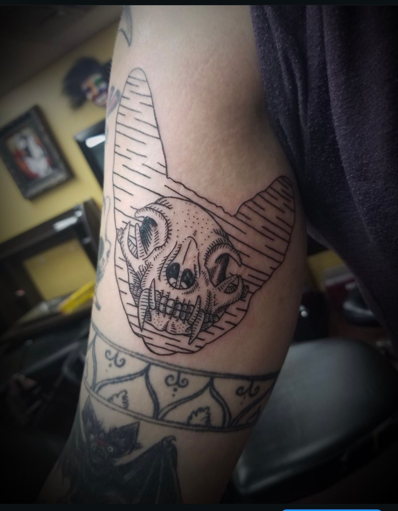 A person has a tattoo of a cat skull on their arm