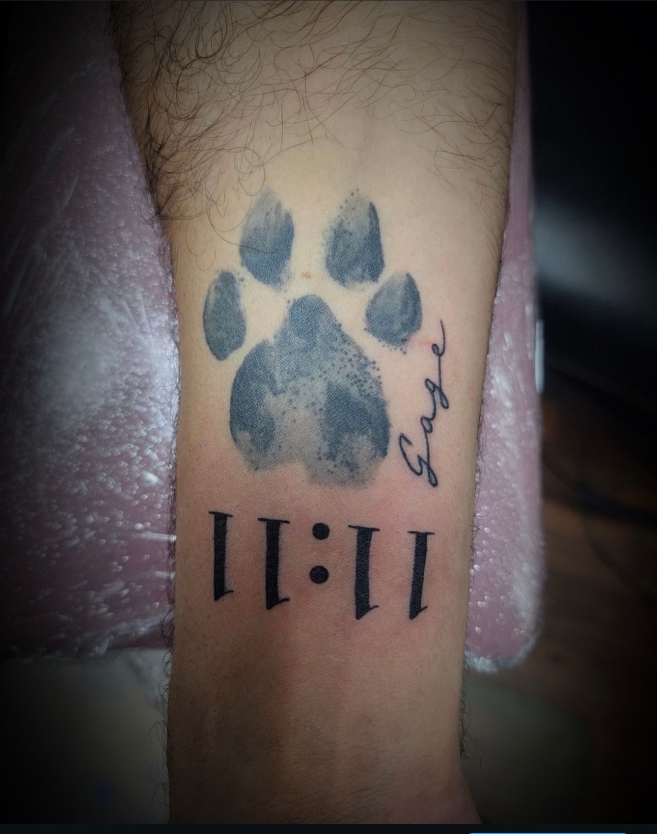 A man has a tattoo of a paw print and the time 11:11